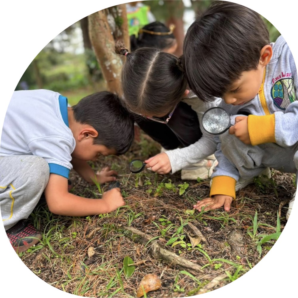 Niños de Casa Wari observando el suelo con lupas
